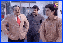 three men are standing next to each other in front of a sign that says sony televisions