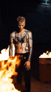 a tattooed man stands in front of a fire that says anarchy on his chest