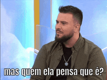 a man with a beard is sitting in front of a screen that says mas quem ela pensa que e?