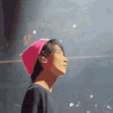 a man wearing a pink scarf around his head looks up at the sky