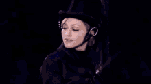 a woman in a top hat is dancing on a stage in front of a blue background .