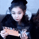 a woman is holding a card in her hands and making a face .