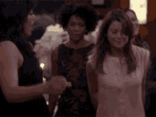 a group of women are standing next to each other in a room and dancing .