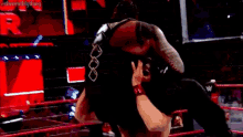 a wrestling match is taking place in a ring with a red ring .