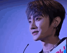 a close up of a young man standing in front of a microphone with his eyes closed .