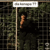a man standing in front of a fence with dia kenapa written on the top