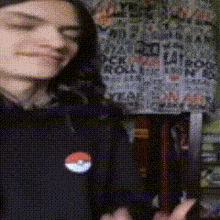 a blurry picture of a person wearing a black shirt with a pokemon button on it