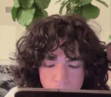 a woman with curly hair is sitting in front of a tablet with her eyes closed