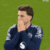 a man with a beard is wearing a blue adidas shirt on a soccer field .