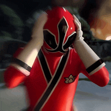 a red samurai power ranger is holding his head with his hands