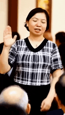a woman in a plaid shirt is standing in front of a crowd of people .