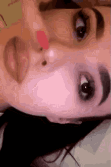 a close up of a woman 's face with a red spot on her nose .