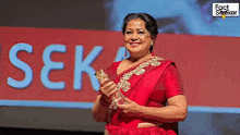a woman in a red dress is holding a trophy and smiling .