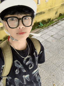 a young boy wearing glasses and a helmet is standing on a tiled sidewalk