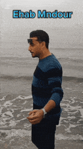a man standing on a beach with the name ehab mndour on the top