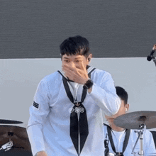 a man in a sailor uniform is covering his face with his hand