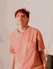 a man with red hair is wearing a pink t-shirt with a smiley face on it