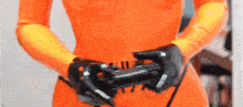 a woman in a latex suit is holding a video game controller .