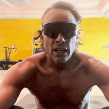 a man without a shirt is wearing black sunglasses
