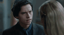 a man in a suit and tie looks at a woman in a beanie