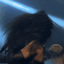 a woman singing into a microphone with her hair blowing in the air