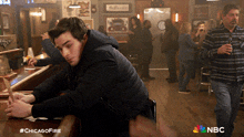 a man sits at a bar with the hashtag #chicagofire on the bottom