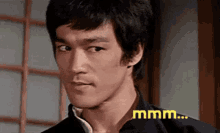 a close up of bruce lee 's face with the word mmmm written on the bottom .