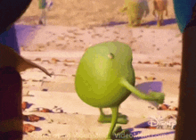 a green monster from disney 's monsters inc is dancing on the beach