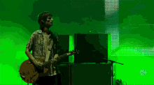 a man is playing a guitar in front of a green background that says ' music festival ' on the bottom