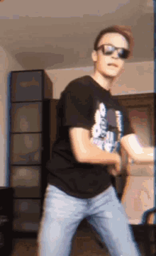a young man wearing sunglasses is dancing in a living room .