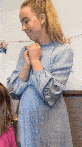 a woman in a blue dress holds her hands together in prayer