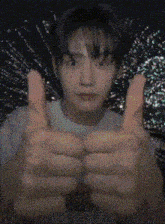a young man is giving a thumbs up sign in front of a black background .