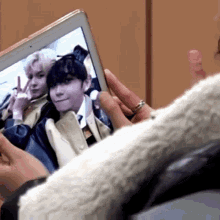 a person is holding a tablet with a picture of two people on the screen