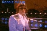 a man in a blue suit singing into a microphone with the name ronnie milsap above him
