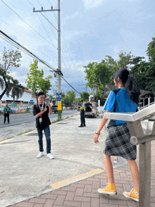 a man taking a picture of a girl on the side of the road with a sign that says " no parking "