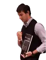 a man in a vest is holding a book and a pen .