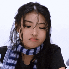a woman wearing a black shirt and a blue scarf makes a sad face