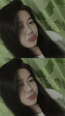 a girl with long black hair laying on a green curtain