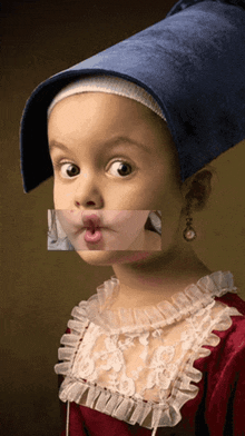 a little girl wearing a blue hat and a red dress making a face