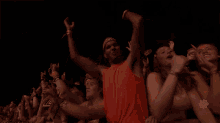 a crowd of people at a concert with a man wearing an orange shirt that says ' i love you ' on the front