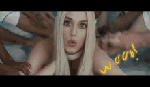 a woman with blonde hair is surrounded by people and the word wow is written on her back