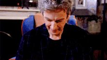 a man in a plaid shirt is sitting in a chair and looking down .