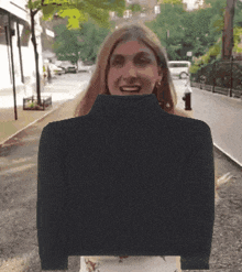 a woman is wearing a black turtleneck sweater and smiling