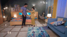 a man and a woman are standing in a bedroom with a blue couch