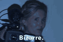 a woman is holding a camera with the word bizarre on the bottom