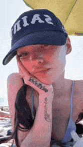 a woman with a tattoo on her wrist wearing a hat that says nia2