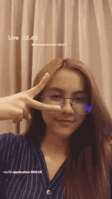 a woman wearing glasses giving a peace sign with the time of 22.45