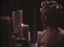 a woman with curlers in her hair is blowing a kiss in front of a candle holder .