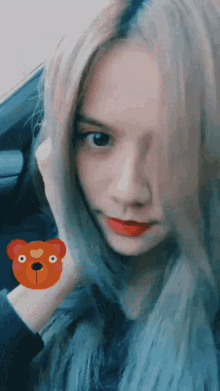 a woman with a teddy bear on her face looks at the camera