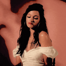a woman wearing a white off the shoulder top and hoop earrings